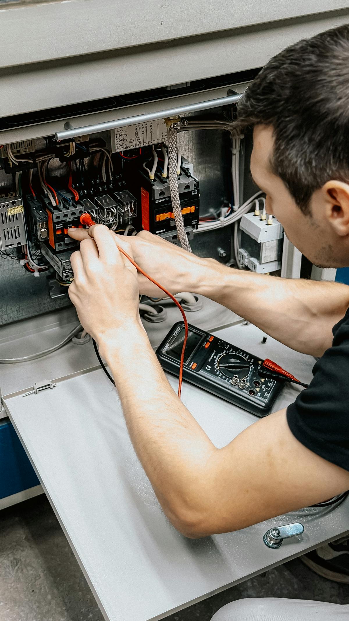 Multimeter testing connections in an open panel