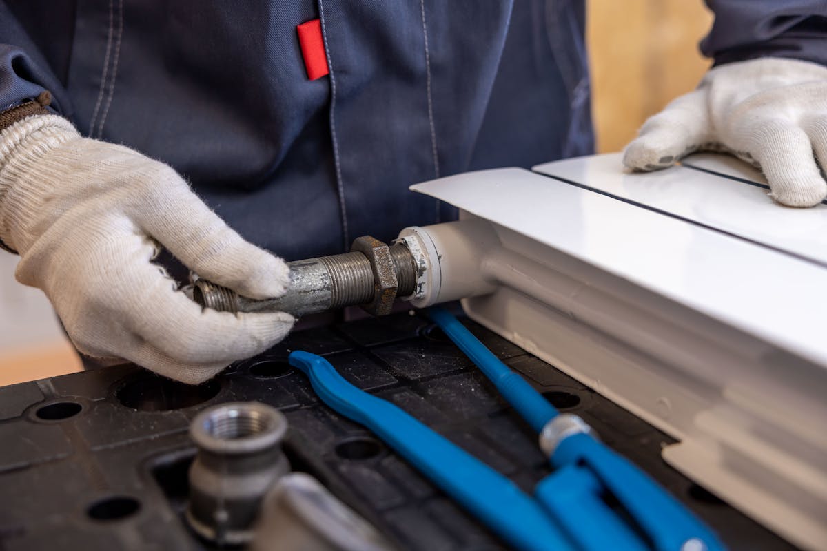 Plumber installing a radiator pipe with hand tools