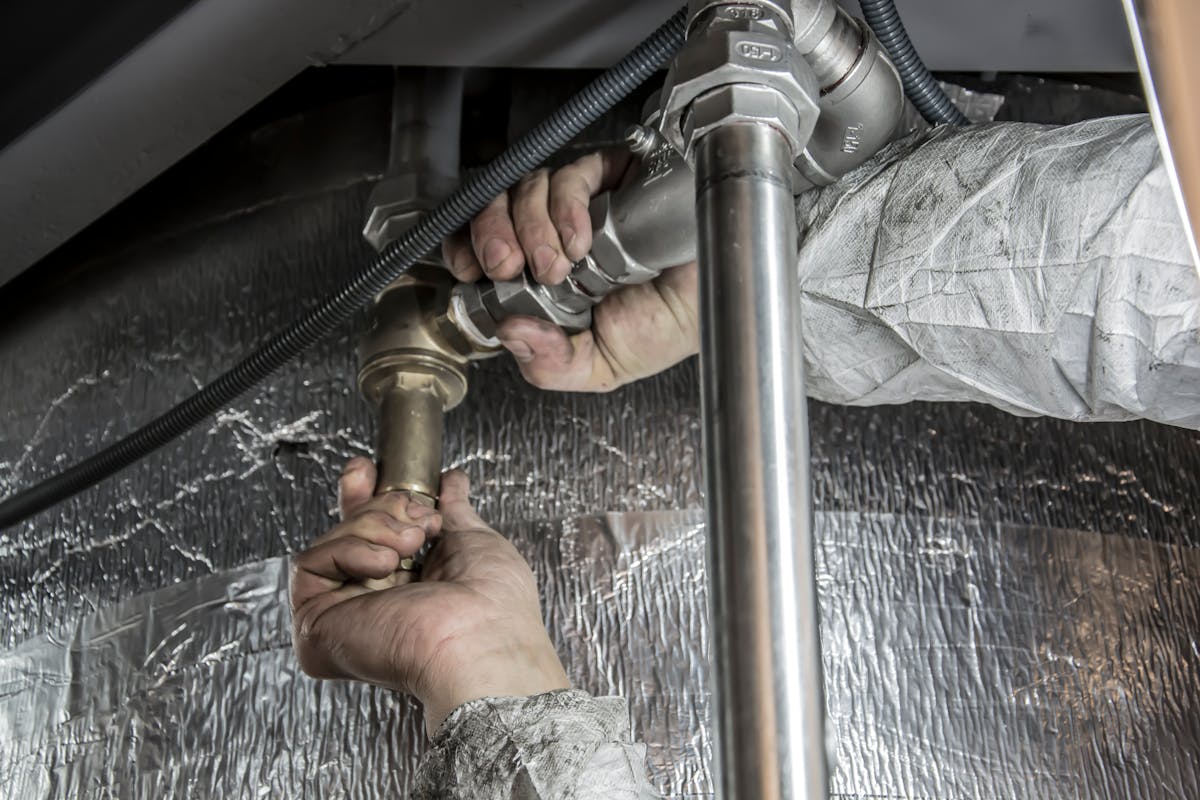 Hands fitting a length of steel pipe in a tight working space